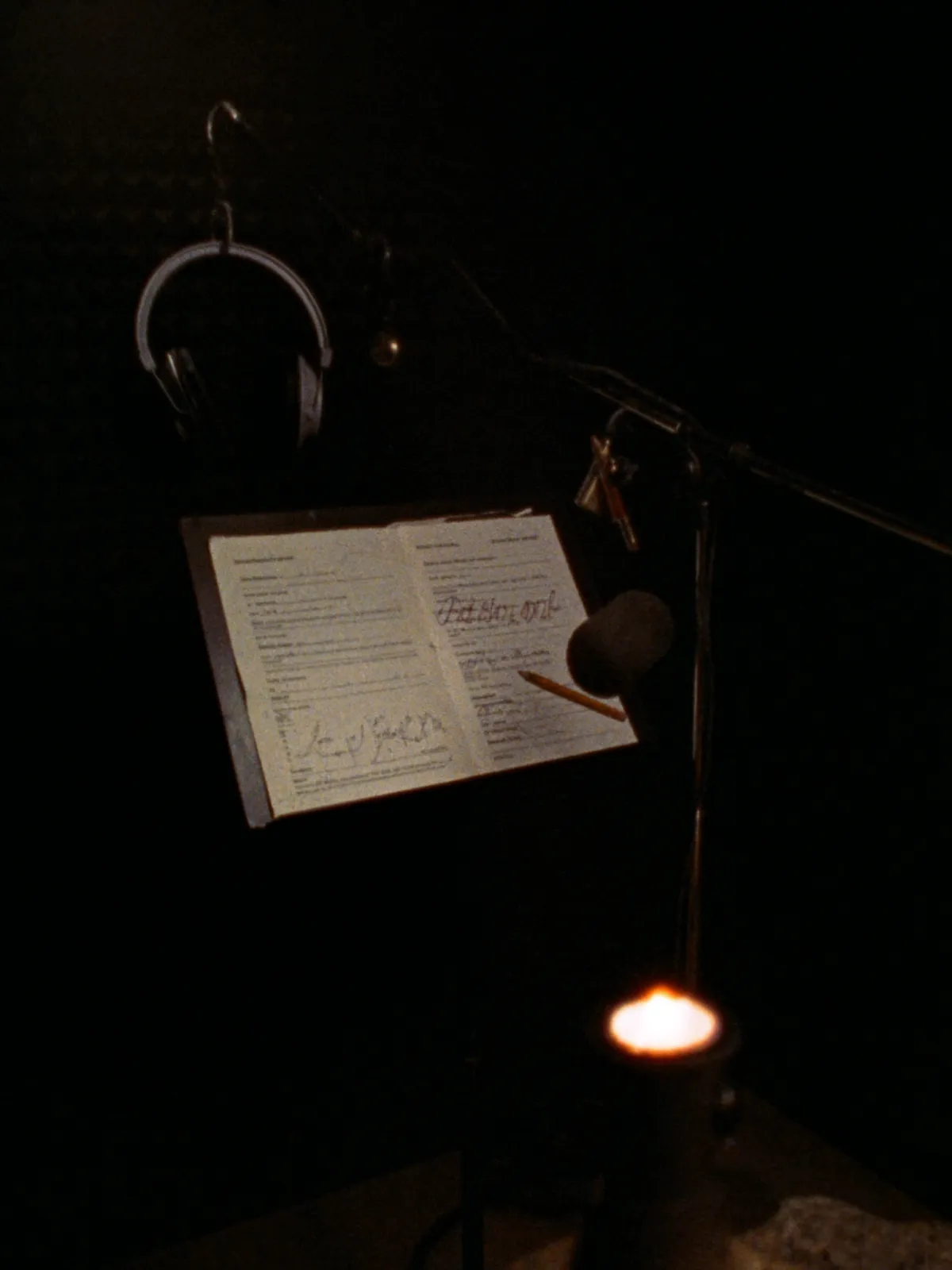 A small sound booth with a microphone, headphones and an annotated script