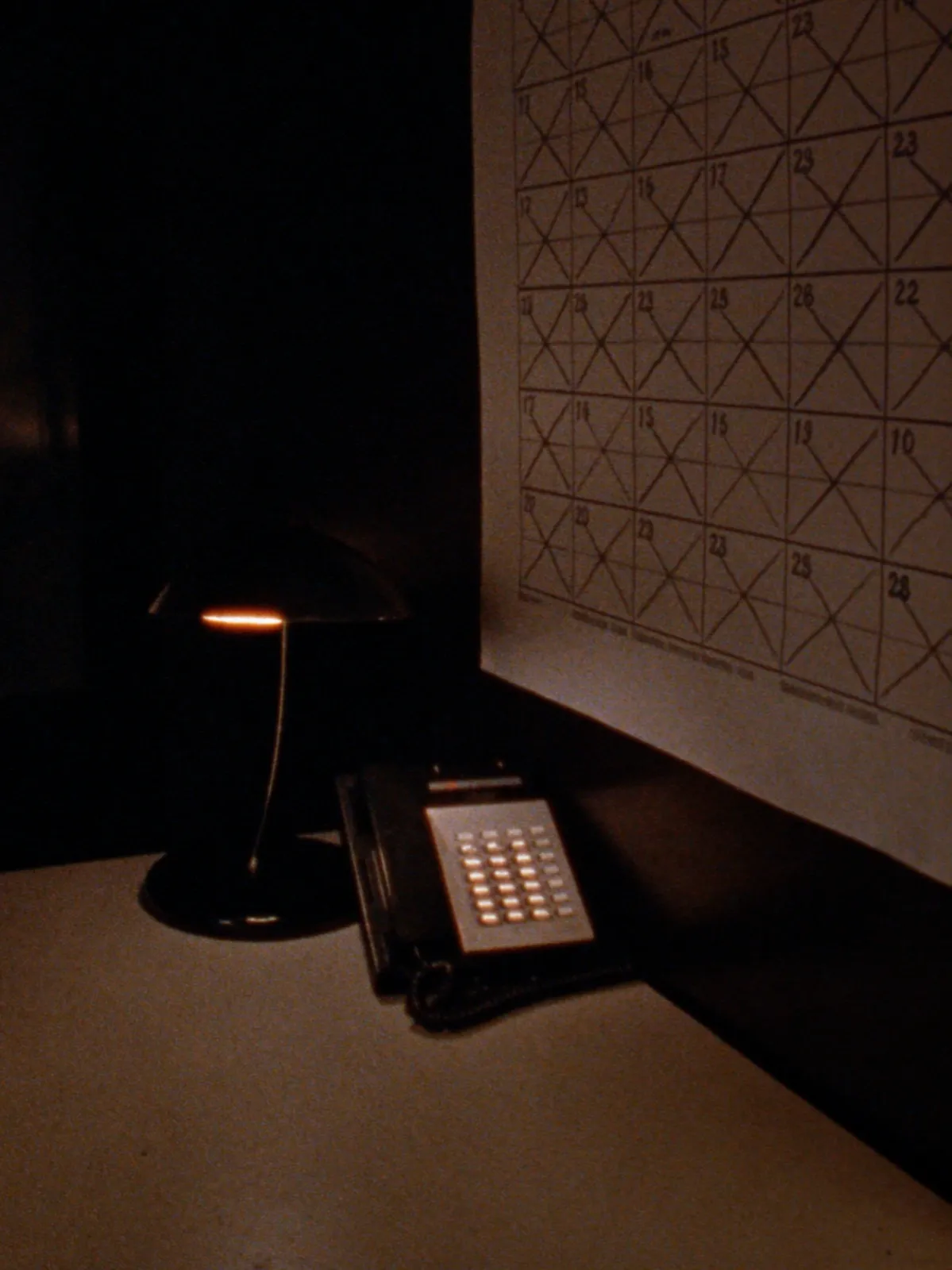 A sales desk at first light with a desk phone and a crossed-off wall calendar