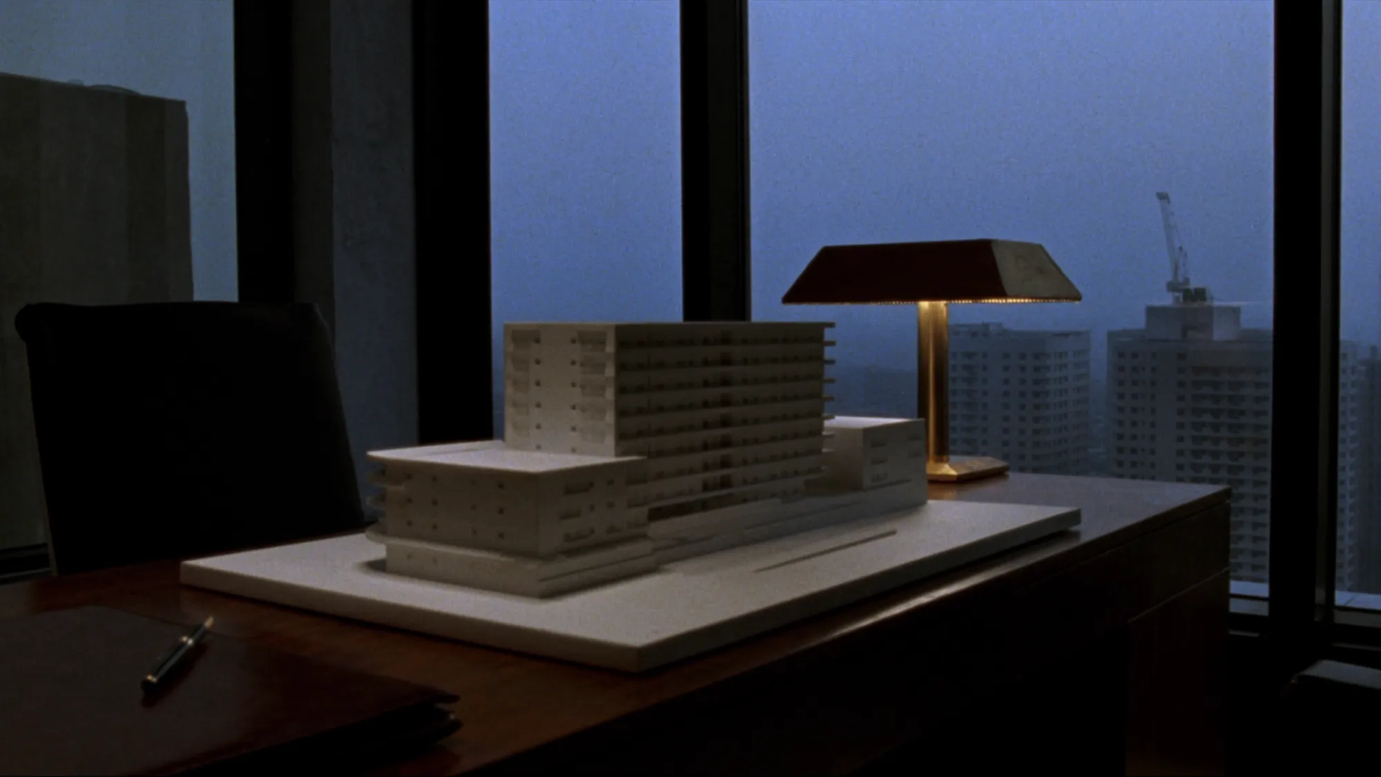 A private investment office at dusk with an architectural model on the desk